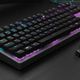 Clavier mécanique rétroéclairé avec plusieurs keycaps retirées posées à côté sur un bureau sombre