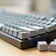 Clavier mecanique aux keycaps vierges pose sur un bureau en bois, trois keycaps retirees a cote